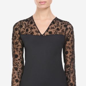Camiseta Avet 77111 negra de manga larga con transparencias y flores de terciopelo Título de la imagen Camiseta Avet 77111 negra con flores de terciopelo Marca Avet Descripción corta La camiseta Avet 77111 de manga larga combina un cuerpo negro liso con elegantes transparencias y motivos florales de terciopelo en escote, hombros y mangas. Un diseño femenino y sofisticado, disponible en tallas M y L. Composición: 90% poliamida y 10% elastómero. Descripción larga La camiseta Avet 77111 destaca por su elegante combinación de tejido negro liso y transparencias florales, creando una prenda de lencería femenina con un diseño muy especial. La parte del cuerpo presenta un acabado negro liso, mientras que la zona superior, los hombros y las mangas están confeccionados en tejido transparente decorado con motivos florales de terciopelo negro. Su escote en pico realza el diseño y está rematado de forma sencilla para dejar todo el protagonismo a las transparencias y al dibujo floral. Las mangas largas transparentes continúan con el mismo motivo de flores de terciopelo, consiguiendo un bonito contraste con la parte opaca del cuerpo. Está confeccionada en 90% poliamida y 10% elastómero, una composición que proporciona elasticidad y adaptación. Una camiseta negra elegante y diferente, perfecta para quienes buscan una prenda con el atractivo de las transparencias y un delicado acabado floral. Características: - Camiseta de mujer Avet - Referencia 77111 - Color negro - Manga larga - Escote en pico - Cuerpo negro liso - Parte superior transparente - Mangas transparentes - Motivos florales de terciopelo - 90% poliamida y 10% elastómero - Disponible en tallas M y L Para Yoast, escribe exactamente camiseta Avet 77111 en Frase clave objetivo. La he colocado en los puntos importantes para mantener el mismo sistema que estamos utilizando en todos estos productos.